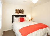 Thumbnail 7 of 14 - a bedroom with a white bed and an orange blanket