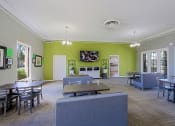 Thumbnail 10 of 21 - a common room with tables and chairs and a television on the wall