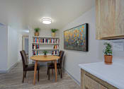 Thumbnail 19 of 24 - A dining room with a round table and chairs, a bookshelf, and a painting on the wall at Connect on Northern, Glendale, AZ 85301