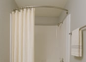 Thumbnail 17 of 24 - A white bathroom with a toilet, a shower with a curtain, and a towel hanging on the wall at Connect on Northern, Glendale, AZ 85301