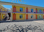 Thumbnail 13 of 16 - A building with yellow, orange, and green doors.