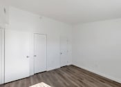 Thumbnail 7 of 14 - a bedroom with white walls and wooden floors and two closets