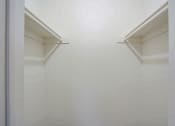 Thumbnail 10 of 14 - a closet with white walls and two white shelves