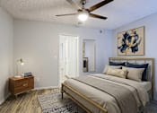 Thumbnail 8 of 23 - A bedroom with a bed, nightstand, and artwork on the wall.