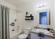 Thumbnail 22 of 30 - A bathroom with a white toilet, a sink, and a shower curtain.