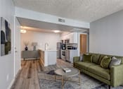 Thumbnail 5 of 16 - A living room with a green couch and a coffee table.