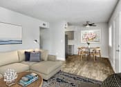 Thumbnail 3 of 19 - A living room with a beige couch, a coffee table, a ceiling fan, and a painting on the wall at Gilbert Square Apartments, Mesa, AZ 85203