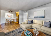 Thumbnail 4 of 19 - A living room with a beige couch, a coffee table, and a painting on the wall at Gilbert Square Apartments, Mesa, AZ 85203