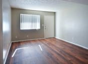 Thumbnail 7 of 19 - A room with wooden floors and a window with blinds at Gilbert Square Apartments, Mesa