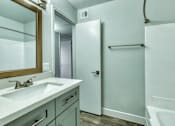 Thumbnail 14 of 19 - A bathroom with a white tub, sink, and towel rack at Gilbert Square Apartments, Mesa, AZ