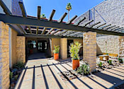 Thumbnail 27 of 36 - leasing office entrance: A patio with a pergola and potted plants.