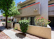 Thumbnail 88 of 94 - A building with a red stripe on the side has a tree and bushes in front of it.