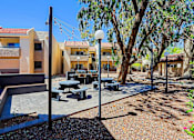 Thumbnail 35 of 36 - A sunny day at a modern outdoor seating area with picnic tables and benches.
