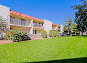 Thumbnail 25 of 25 - A building with a red roof and a green lawn in front.