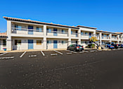Thumbnail 11 of 13 - an apartment building with a parking lot and cars in front of it