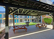 Thumbnail 16 of 19 - A wooden picnic table is under a roof on a patio.