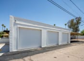 Thumbnail 7 of 7 - a small white building with three garages on the side of it