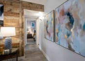 Thumbnail 7 of 24 - a hallway with paintings on the wall and a door to a bedroom