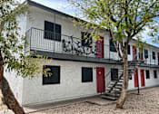 Thumbnail 14 of 20 - A white building with a red door and a bicycle hanging on the balcony.