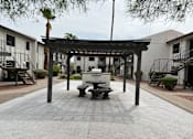 Thumbnail 15 of 18 - A patio with a table and chairs under a pergola.