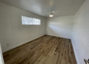 Thumbnail 6 of 6 - an empty living room with wood flooring and a ceiling fan