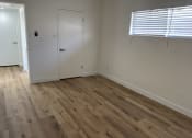 Thumbnail 5 of 6 - a bedroom with wooden floors and white walls and a door
