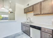 Thumbnail 6 of 10 - a kitchen with white walls and wooden cabinets