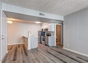Thumbnail 6 of 16 - A kitchen with white cabinets and a wooden floor.