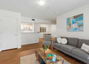 Thumbnail 6 of 15 - a living room with a couch coffee table and a kitchen in the background