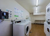Thumbnail 15 of 16 - A laundromat with washers and dryers and a wall of posters.