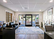 Thumbnail 18 of 25 - A reception area with a black couch, a desk, and a framed picture on the wall.