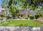 Thumbnail 74 of 94 - A sunny day at a residential complex with a well-maintained lawn and trees.