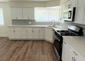 Thumbnail 5 of 8 - a kitchen with white cabinets and a black stove top oven