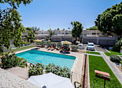 Thumbnail 62 of 94 - A pool surrounded by a fence and a patio with chairs.