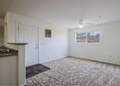 Thumbnail 2 of 21 - A room with a carpeted floor, a ceiling fan, and a window showing a barren landscape outside.