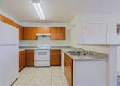 Thumbnail 1 of 21 - A kitchen with white appliances and wooden cabinets.