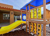 Thumbnail 18 of 21 - A playground with a yellow slide and a wooden structure with the word "BETTER" spelled out on it.