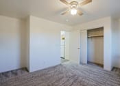 Thumbnail 8 of 15 - A room with a ceiling fan and carpeted floor.