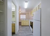 Thumbnail 2 of 15 - A kitchen with a white refrigerator and wooden cabinets.
