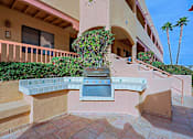 Thumbnail 14 of 15 - A patio with a grill and a building in the background.