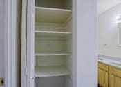 Thumbnail 4 of 15 - A white open closet with shelves and a mirror on the wall.