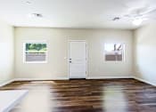 Thumbnail 6 of 29 - A room with a white door and two windows. The floor is hardwood and contrasts against the warm soft yellow walls.