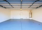 Thumbnail 18 of 29 - A large empty garage with a door and a wall-mounted heater.