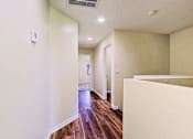 Thumbnail 10 of 29 - A long hallway with wood floors and white walls.