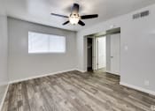 Thumbnail 9 of 9 - an empty living room with a ceiling fan and a door to a hallway