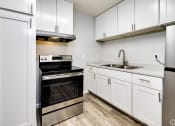 Thumbnail 4 of 9 - an empty kitchen with white cabinets and stainless steel appliances