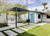 Thumbnail 2 of 9 - a small white house with a blue door and a yard with a stone walkway