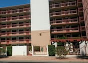 Thumbnail 2 of 5 - A large red brick building with balconies and a white door in front at Ambassador West Apartments, Phoenix
