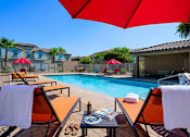 Thumbnail 26 of 29 - A poolside area with chairs and umbrellas.