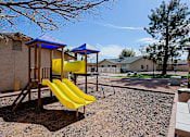 Thumbnail 13 of 15 - A playground with a yellow slide and a blue roofed structure.